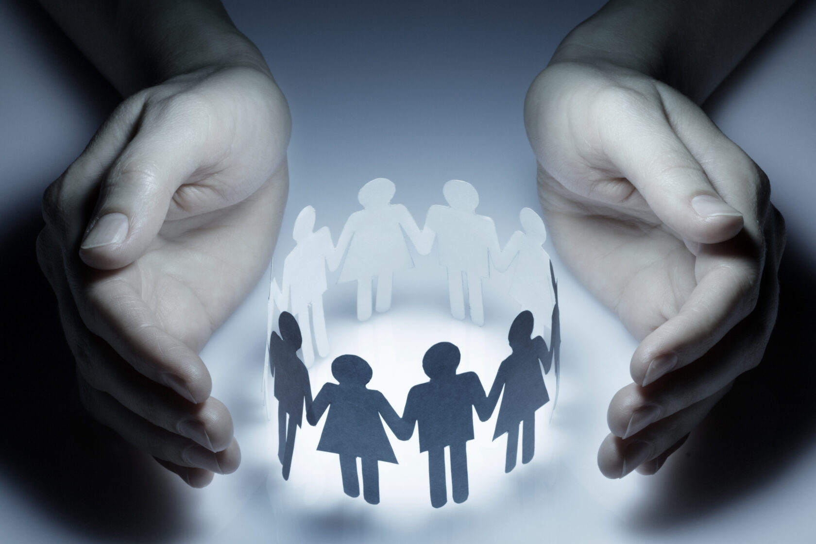 Hands sheltering a circle of paper figures, a symbol of dignity and mutual support